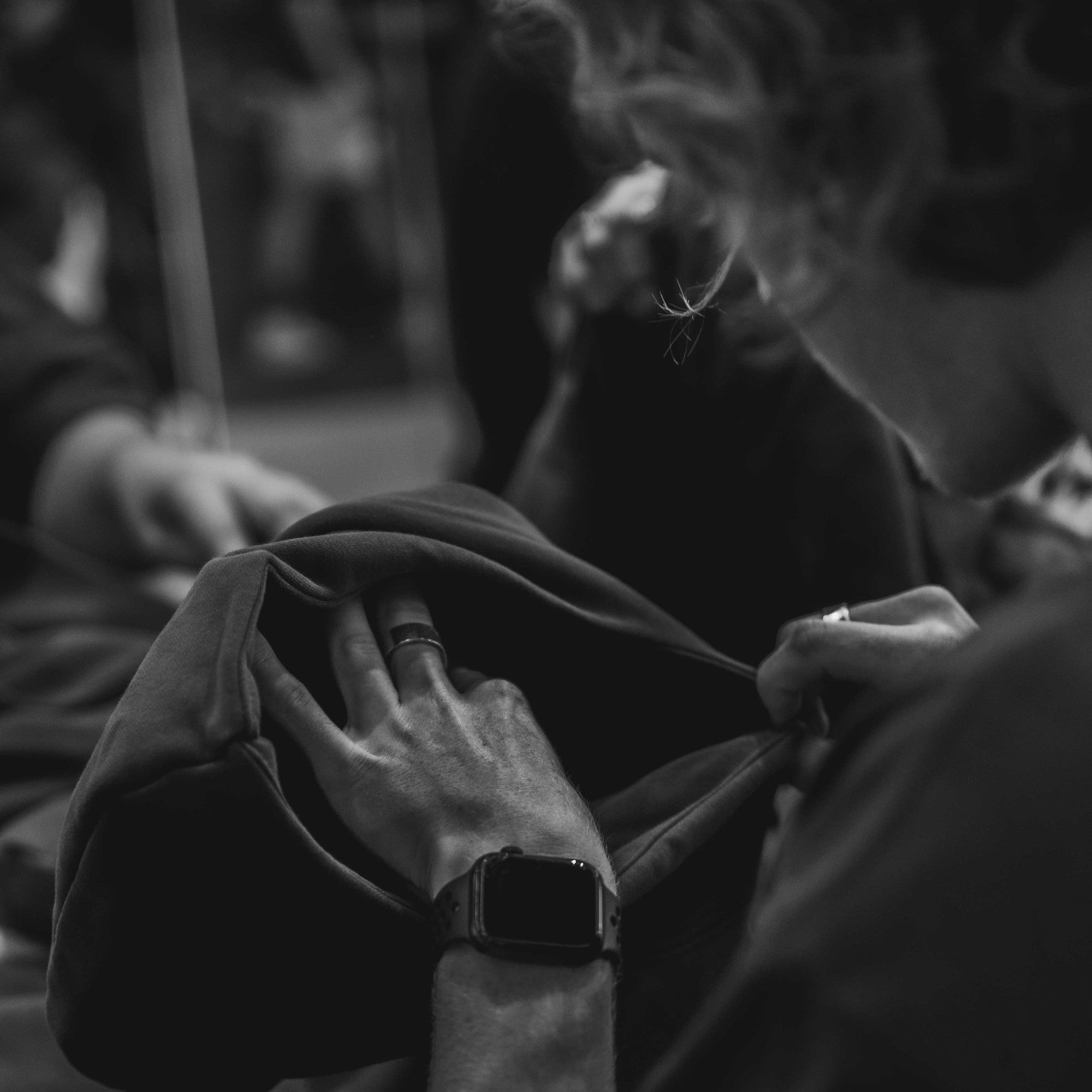 Hands inspecting a finished garment, in black and white.