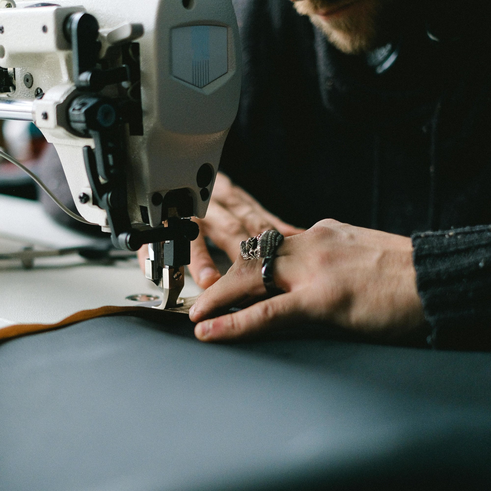 Hands guiding fabric through a sewing machine.